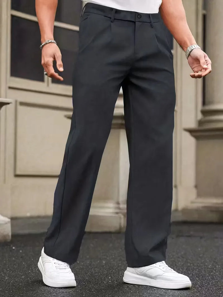 Vooraanzicht van modieuze herenbroek met geplooide details en rechte, losse pijpen, voor een smart casual uitstraling.
