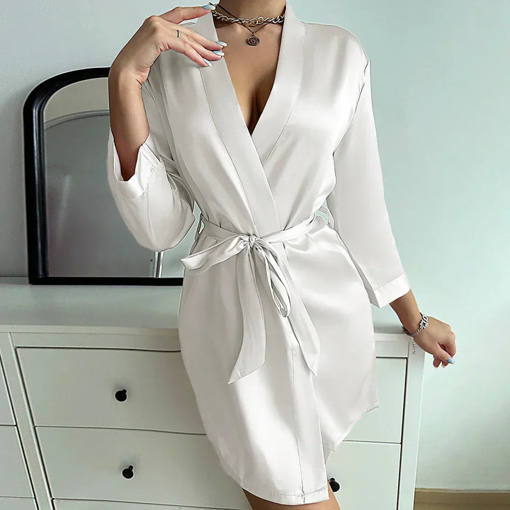 Vrouw draagt de elegante Noémie ochtendjurk van glacé zijde, comfortabele loungewear met vetersluiting.