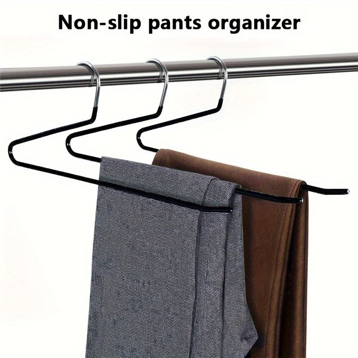 Zwarte metalen broekhangers in gebruik, die de kastorganisatie verbeteren en kleding kreukvrij houden.