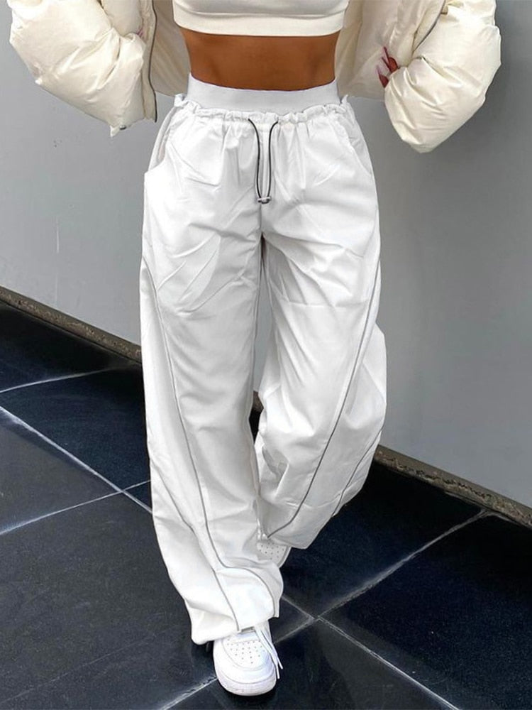 Model draagt een witte dames baggy broek, toont de losse pasvorm en streetwear stijl.
