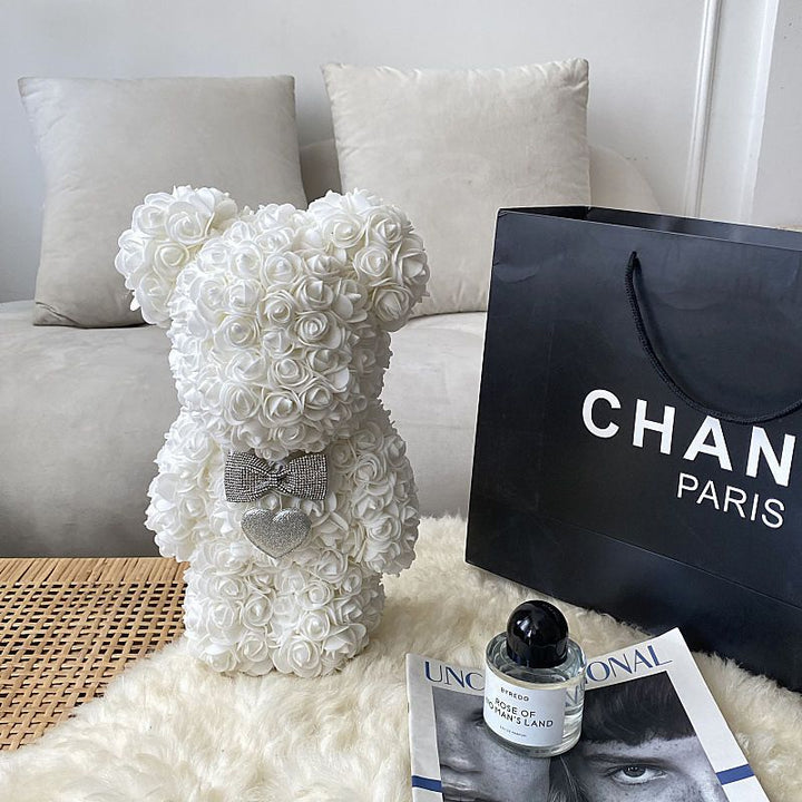 Zachte teddybeer bedekt met rode kunstbloemrozen, prachtig romantisch geschenk.
