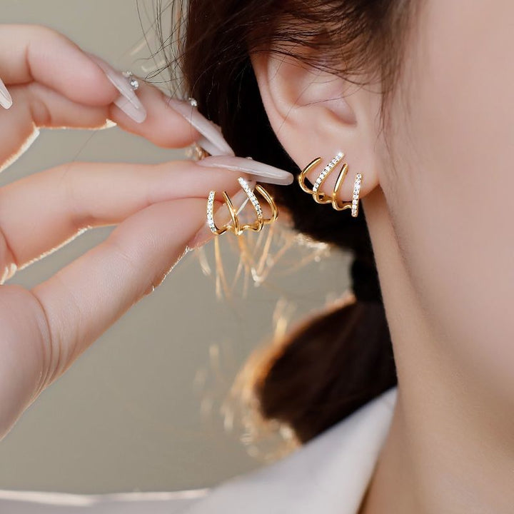 Schitterende dames oorbellen: goudkleurige claw oorstekers met strass, voor een luxe piercing look.