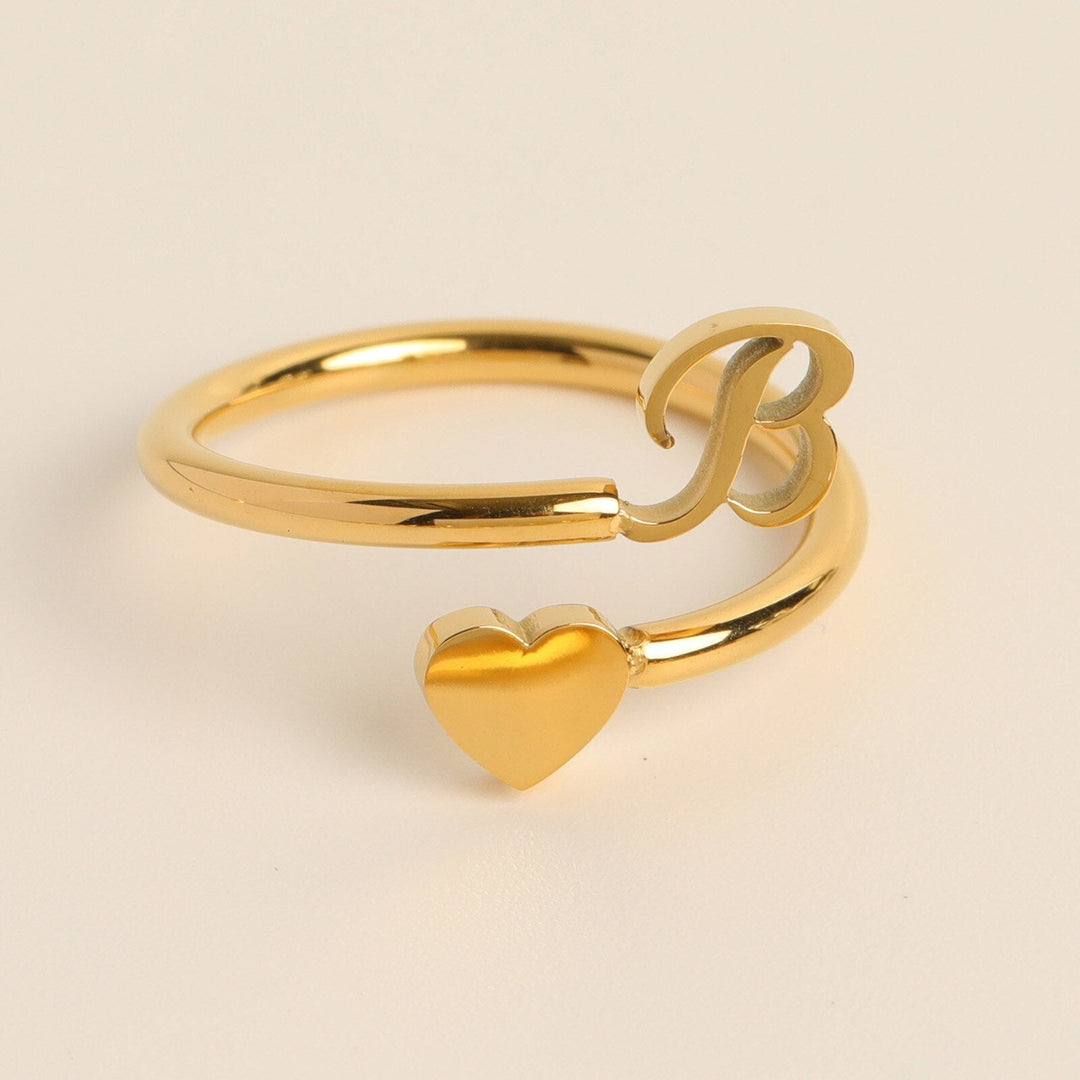 Dames gepersonaliseerde letterring met hart, goudkleurige initialen, modieus accessoire.