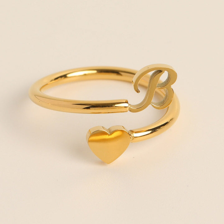 Dames gepersonaliseerde letterring met hart, goudkleurige initialen, modieus accessoire.