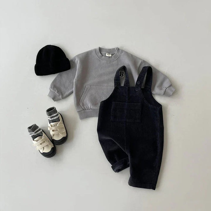 Blije jongen in comfortabele katoenmix kinderoverall, duurzame en trendy tuinbroek. Ideale speelkleding voor jongens.