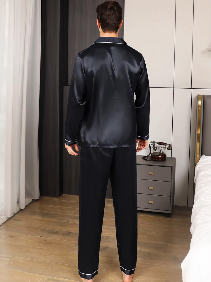Man ontspant in stijlvolle heren pyjama set (lange mouwen/broek). Ideaal voor loungekleding.