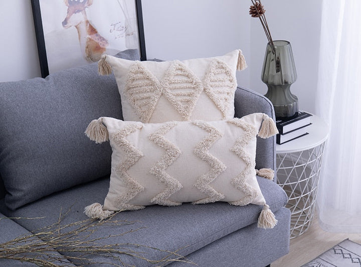 Arrangement van diverse boho sierkussens op een bank, creëert een uitnodigende en warme woondecoratie.