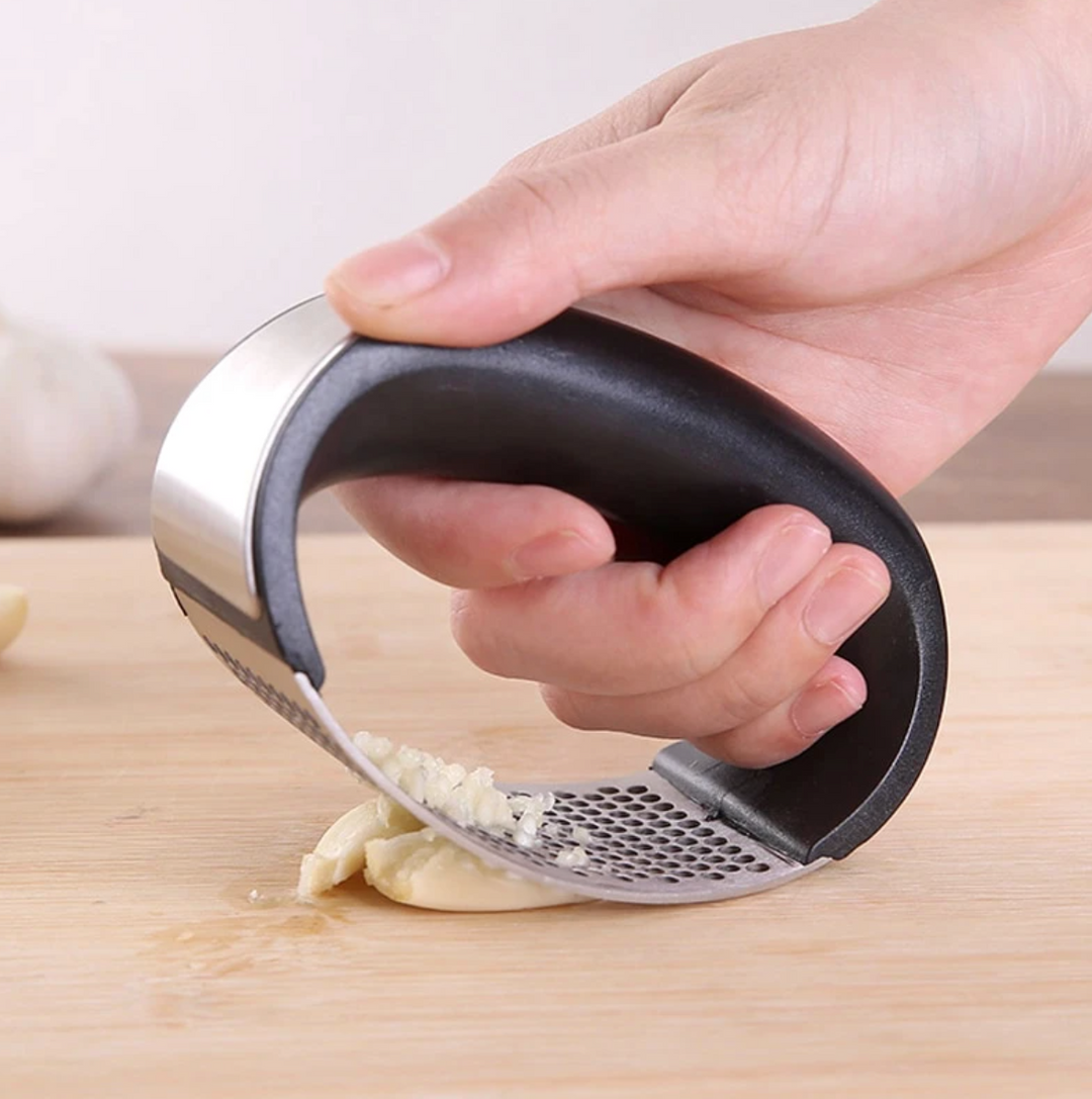 De gebogen knoflookpers van roestvrijstaal, jouw favoriete, makkelijk te hanteren keukengereedschap.