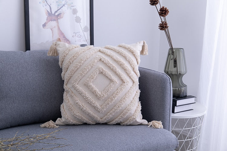 Close-up van een boho kussensloop met gedetailleerde kwastjes en ingeweven geometrisch patroon.