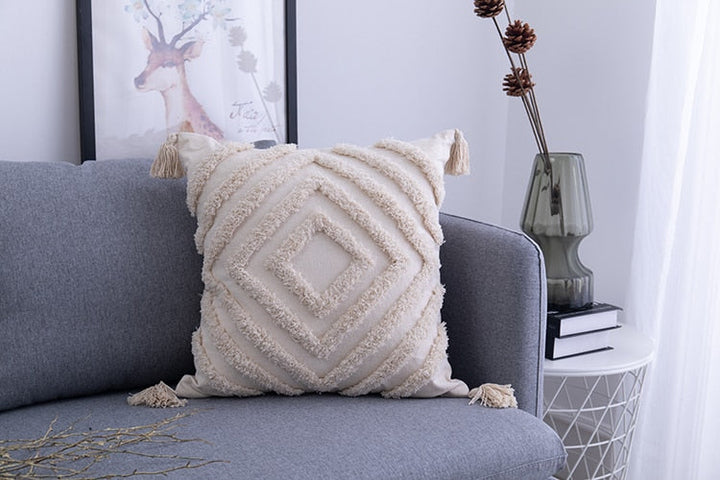 Close-up van een boho kussensloop met gedetailleerde kwastjes en ingeweven geometrisch patroon.
