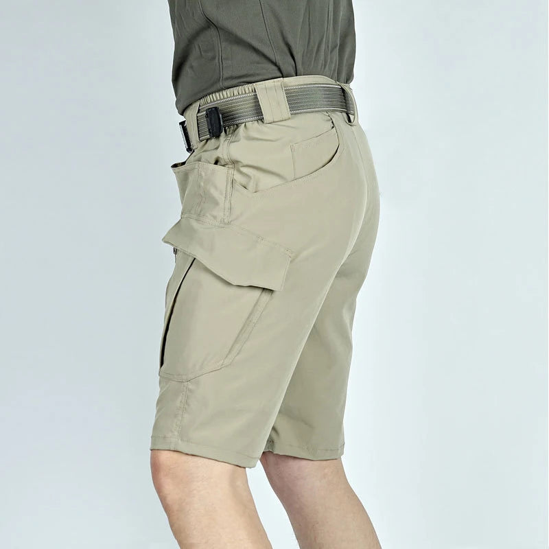 Model draagt mannen tactische cargo short in een outdoor setting, toont bewegingsvrijheid en stijl.