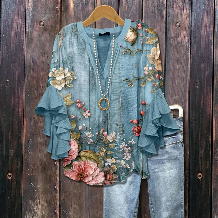 Dames top met romantische blauwe bloemenprint, elegante V-hals en zwierige ruffle mouwen. Perfect voor lente/zomer.