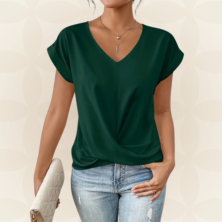 Model draagt elegante dames V-hals top met gedrapeerd detail. Veelzijdige casual/chique zomer top.