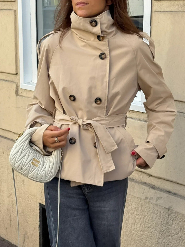 Beige getailleerde dames trenchcoat, waterafstotend en elegant voor elk weer. Klassieke herfstjas.
