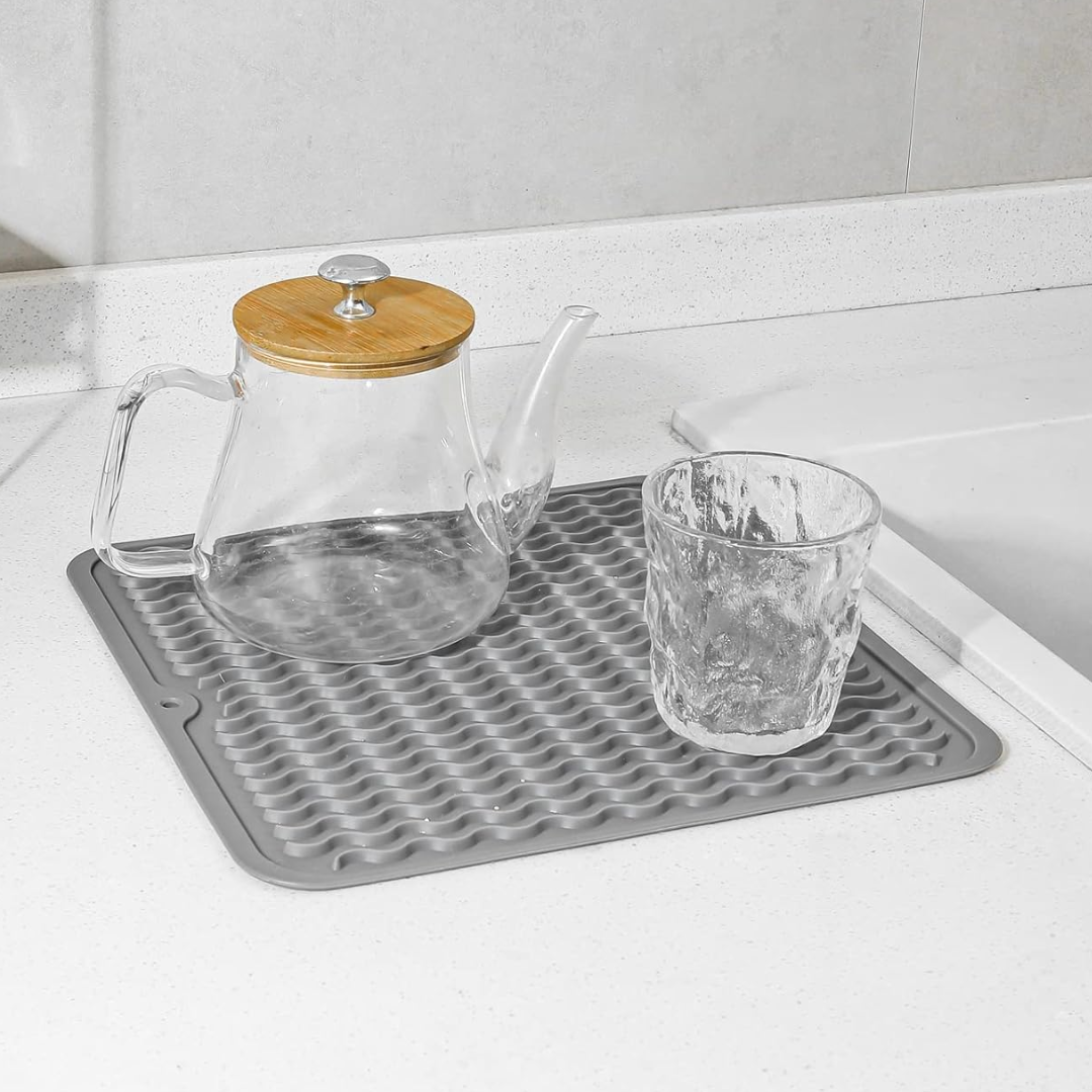 Hand die een blauwe siliconen mat op een aanrecht legt, anti-slip functie.