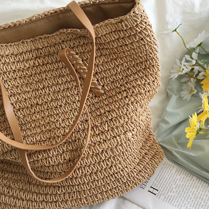 Model toont ruime TerraWoven dames handtas, bruin-wit geweven. Stijlvol en comfortabel accessoire.