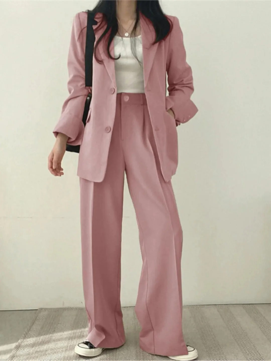 Elegant tweedelig damespak, bestaande uit stijlvol colbert en bijpassende pantalon, voor zakelijke en casual gelegenheden.
