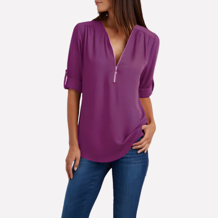 Model draagt een chique damesblouse met halve rits, straalt stijl en comfort uit.