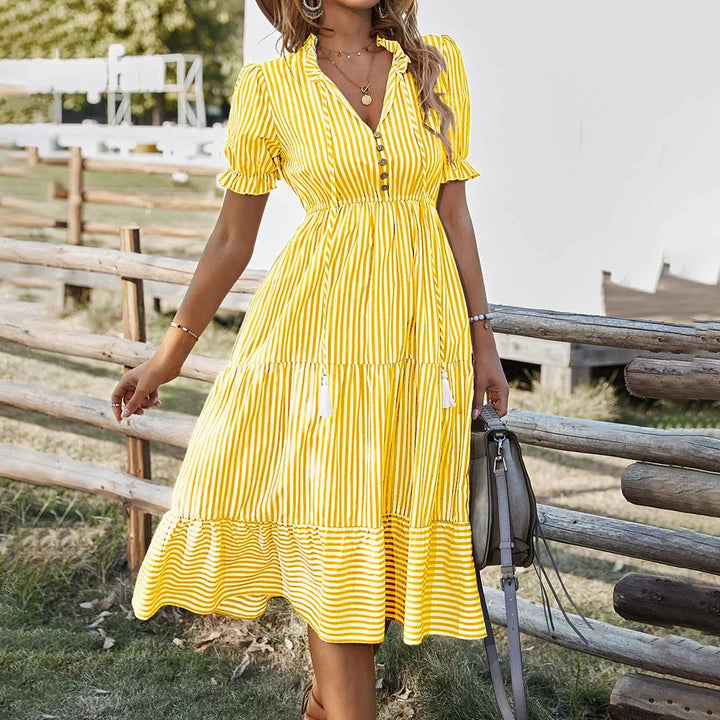 Zomerse gestreepte damesjurk met korte mouwen. Comfortabele casual jurk met knopen en V-hals.