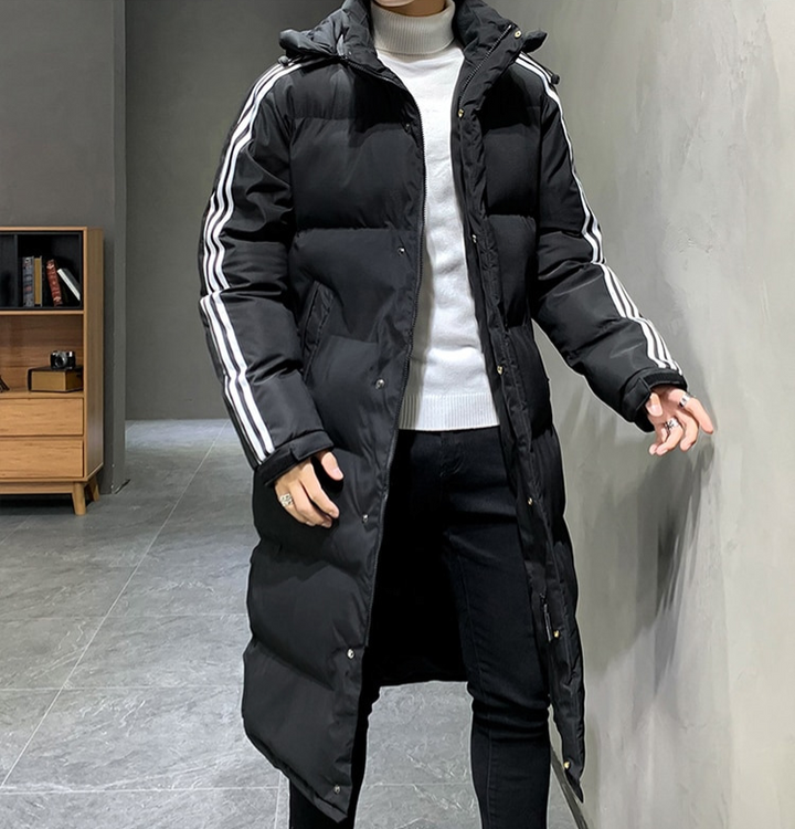 Man draagt zwarte lange gewatteerde winterjas. Sportief design voor heren die warmte en stijl waarderen.
