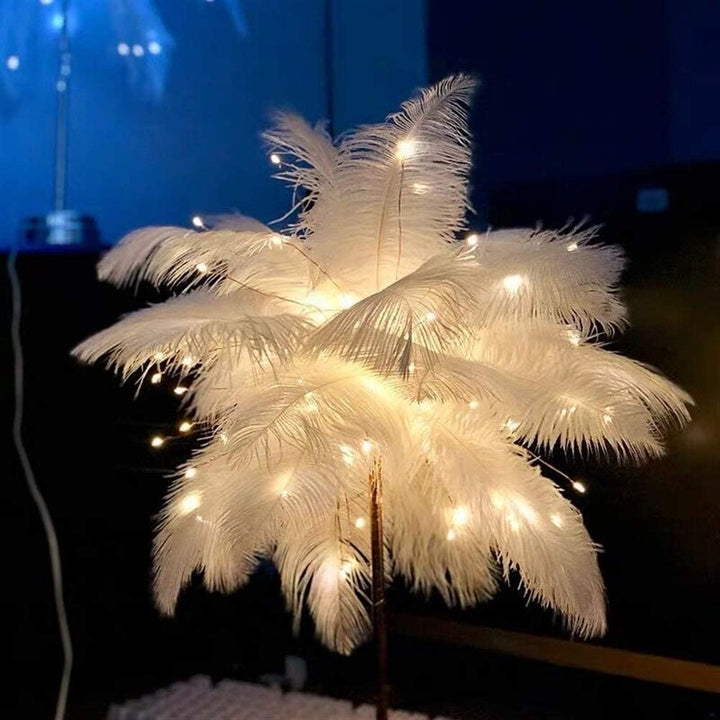 Elegante struisvogelveren nachtlamp met rosegouden voet, gezien vanuit een hogere hoek op een bijzettafel.