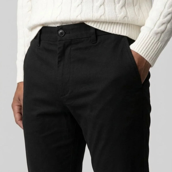 Model draagt zwarte heren chino met regular fit en rechte pijpen, toont de veelzijdige casual stijl.