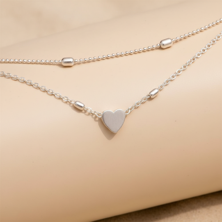 Dames enkelbandje met hartbedel en dubbele ketting. Modern zilveren sieraad, ideaal voor elke outfit.