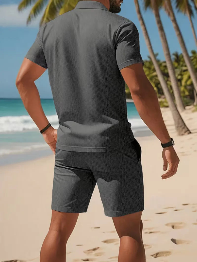 Casual heren vakantieset: lichtblauwe V-hals polo en witte shorts, perfect voor warme dagen.