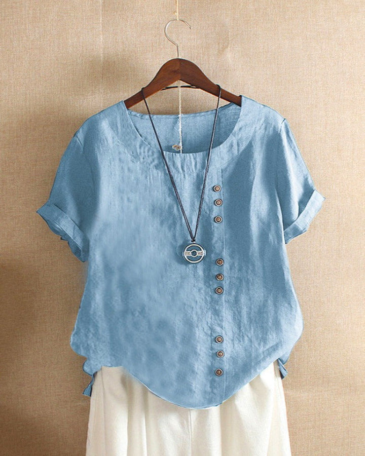 Casual zomeroutfit: dames blouse met korte mouwen en knopen, gecombineerd met jeans.