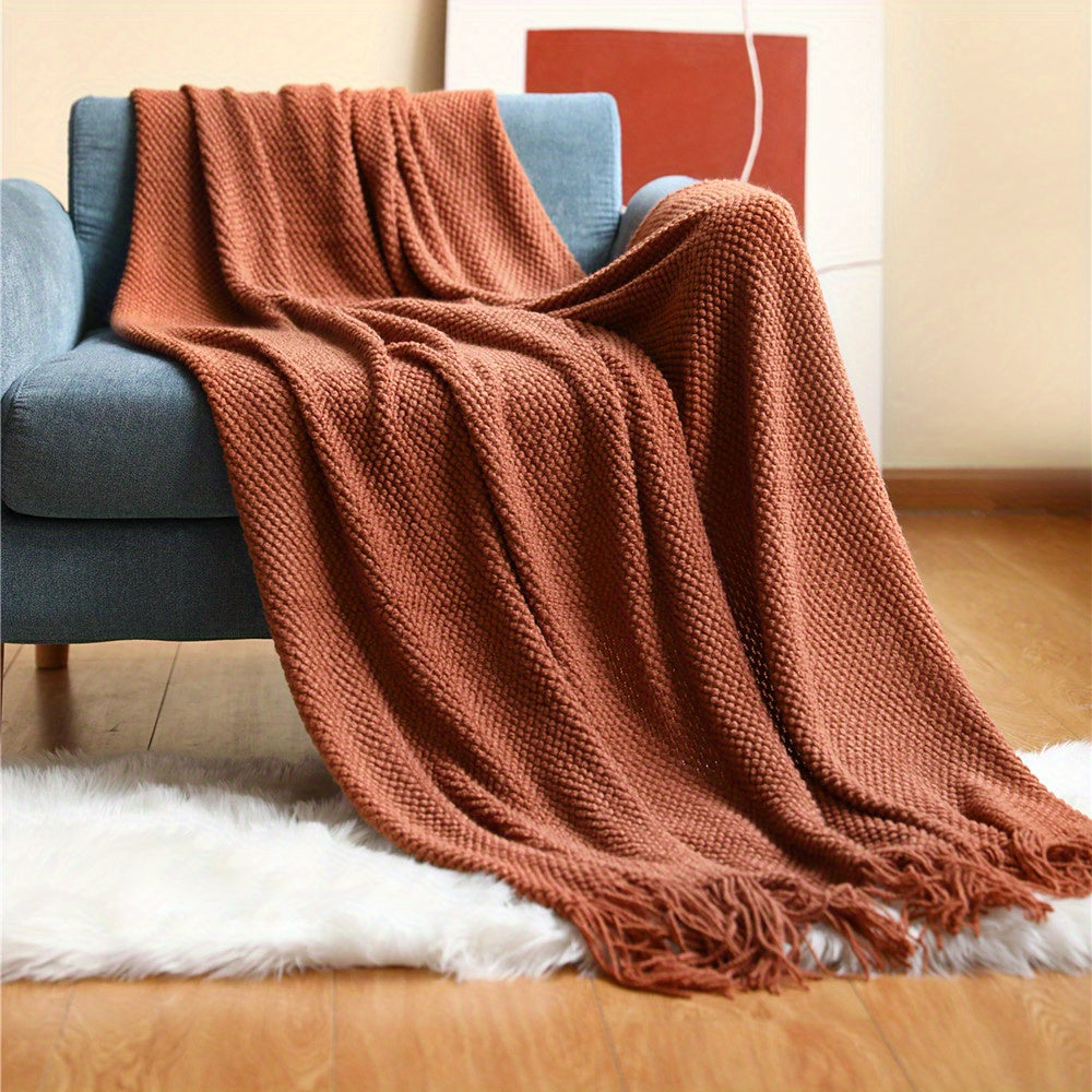 Comfortabele bankdeken van gebreid acryl met speelse kwastjes, ideaal voor gezellige avonden.