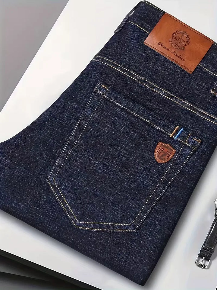 Moderne donkerblauwe heren jeans met rechte pijp, zichtbare stiksels, geschikt voor casual en smart-casual.