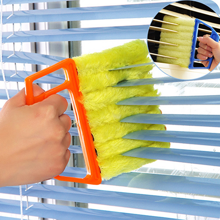 Vrouwenhand gebruikt jaloezieën reiniger met microvezel doek om lamellen efficiënt schoon te maken.