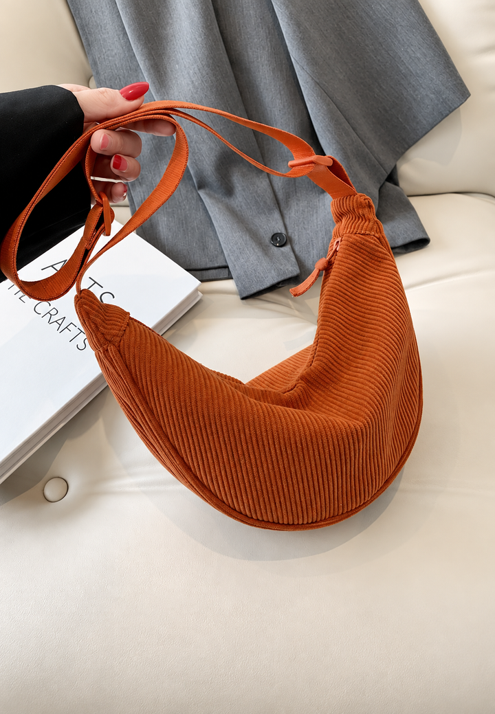 Compacte geribbelde halve maan schoudertas voor dames, draagbaar als crossbody of op de schouder.