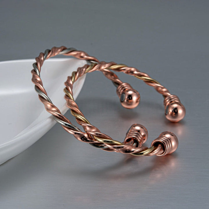 CJ26: Gedraaide koperen bangle met magnetische therapie; unisex design. Goud/roségoud look voor sieraad & comfort.