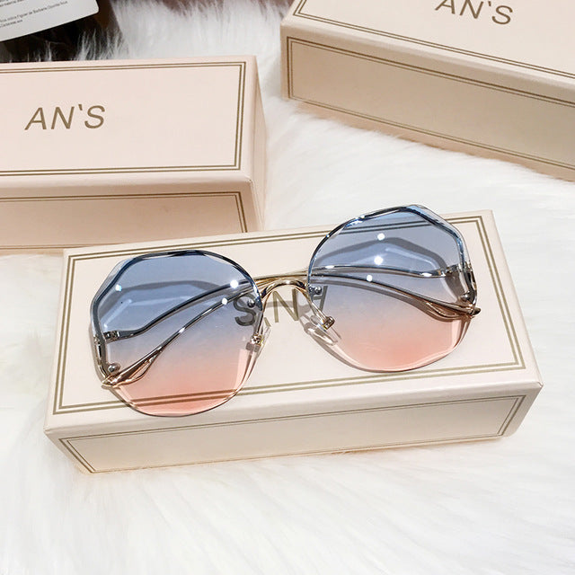 Stijlvolle dames ombre zonnebril met blauw-roze glazen, gouden pootjes en UV-bescherming voor modebewuste zomerlooks.