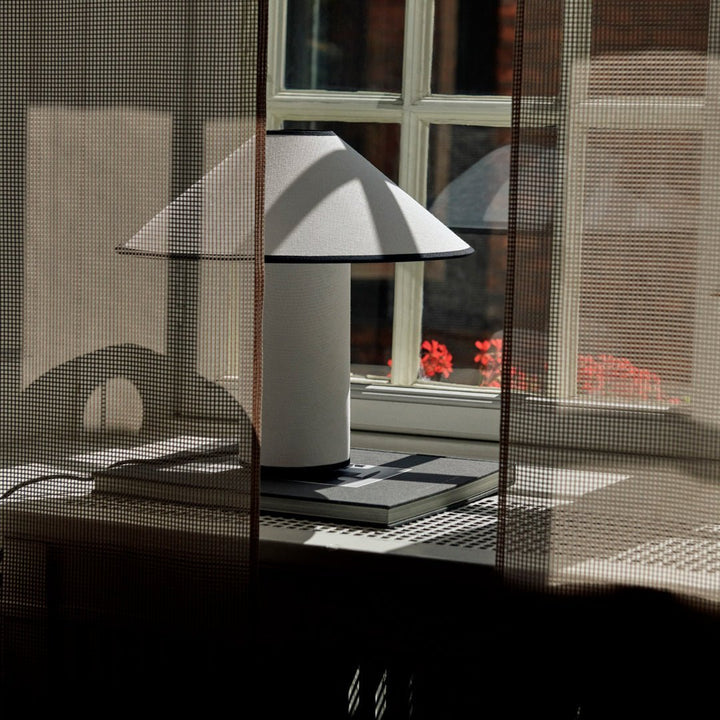 Lunara tafellamp op bijzettafel, de stoffen kap zorgt voor een modern en gezellig sfeerlicht.