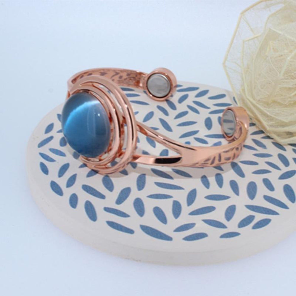Elegante dames manchet armband in retro stijl, met opvallende blauwe cat-eye edelsteen en koperen afwerking.