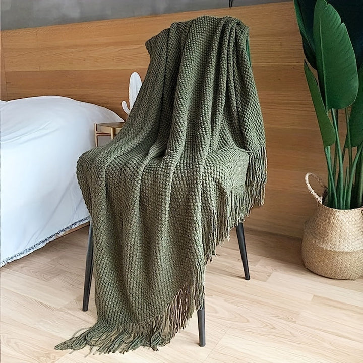 Trendy acryl woondeken met gebreide structuur en kwastjes, een zacht en comfortabel accessoire.
