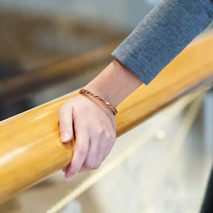 Unisex manchetarmband van gedraaid koper met therapeutische magneten. Stijlvol sieraad voor polsklachten en wellness.