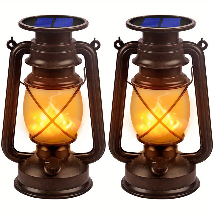 Twee zwarte solar lantaarns met realistische dansende vlam aan in een schemerige tuin setting, voor sfeervolle buitenverlichting.