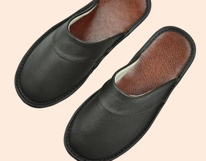 Man geniet van luxe leren herenslippers binnenshuis, voor ultiem comfort en warmte aan de voeten.