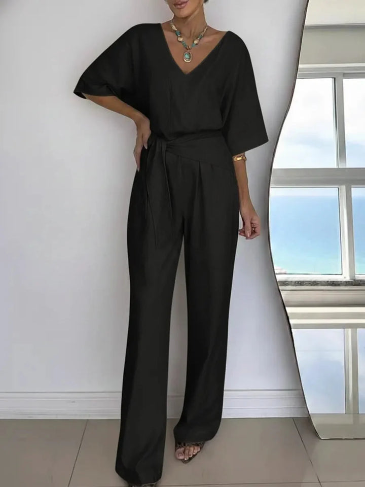 Dames jumpsuit met verfijnde V-hals, losse vleermuismouwen en verstelbare strikceintuur. Elegant & comfortabel.