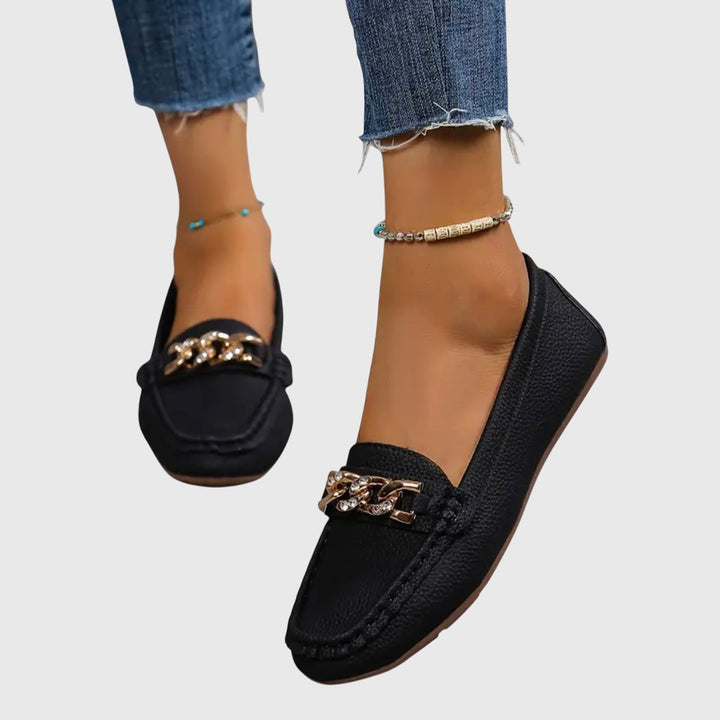 Dames loafers in actie: comfortabele instapschoenen met gouden ketting en platte zool, casual chic.