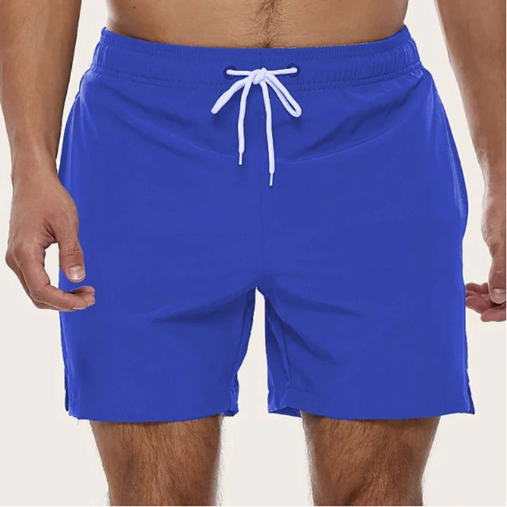 Man geniet van het strand in comfortabele, sneldrogende heren zwemshorts met elastische taille, klaar voor de zomer.