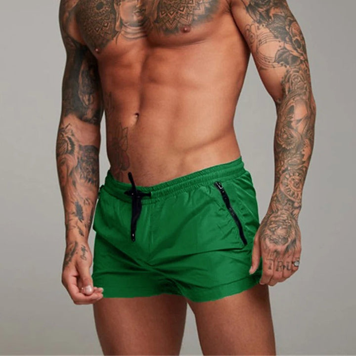 Opgestapelde heren stretch zwembroeken in diverse kleuren, sneldrogend en comfortabel; dé must-have strandkleding voor de zomer.