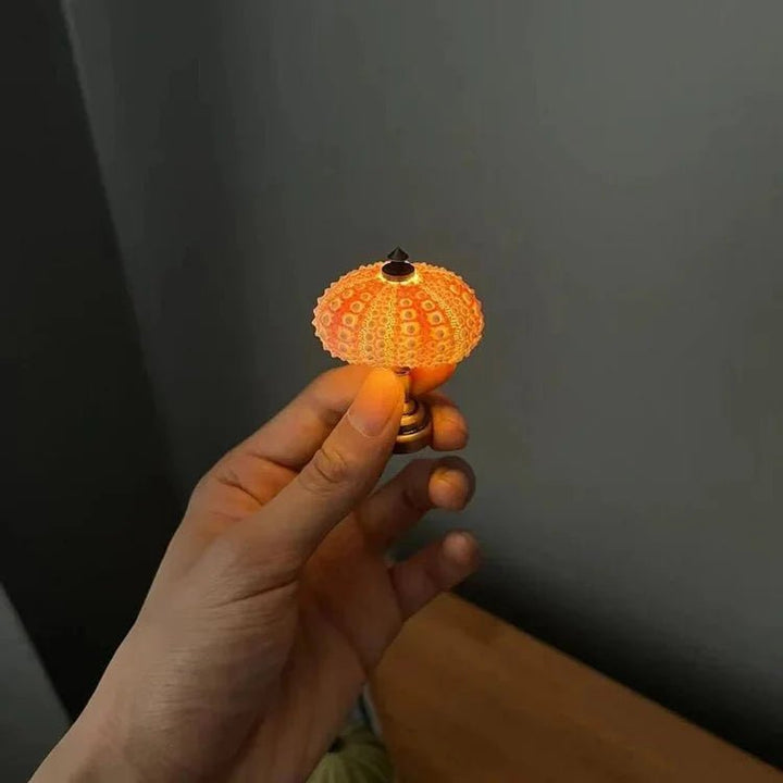 DIY zee-egel nachtlampje op een nachtkastje. Een unieke, sfeervolle lichtbron die rust in de slaapkamer brengt.