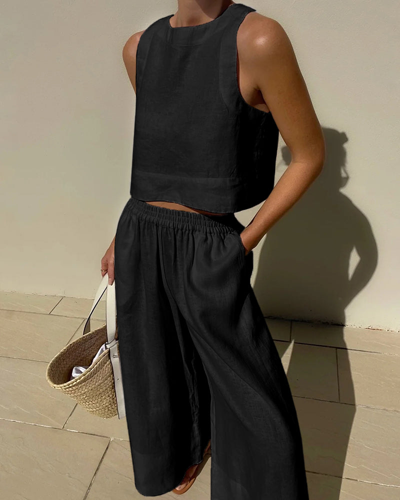 Moderne zwarte tweedelige dames zomeroutfit. Chique crop top en wijd pijpen broek voor een stijlvolle look.