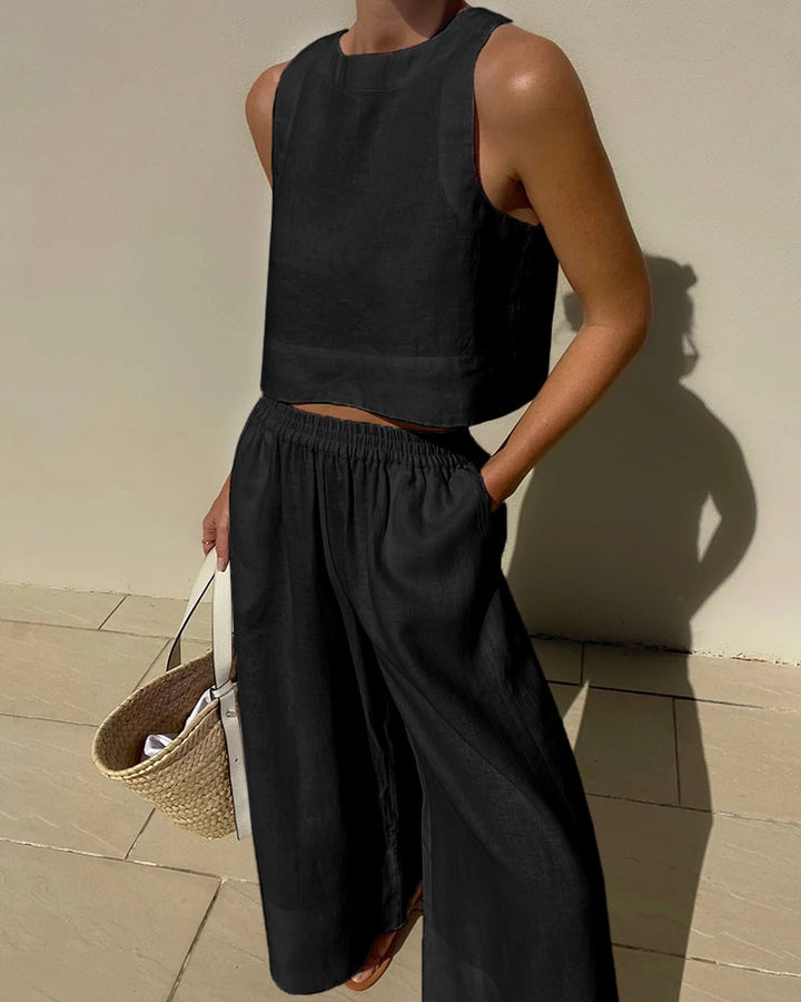 Moderne zwarte tweedelige dames zomeroutfit. Chique crop top en wijd pijpen broek voor een stijlvolle look.
