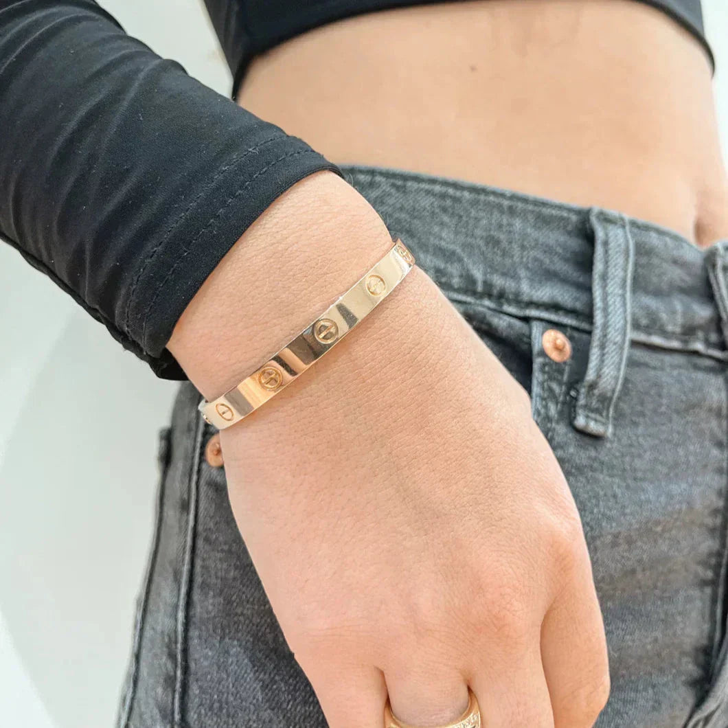 "Elegante gouden armband met tijdloos design en schroefdetails, een verfijnd en luxueus accessoire voor elke gelegenheid."