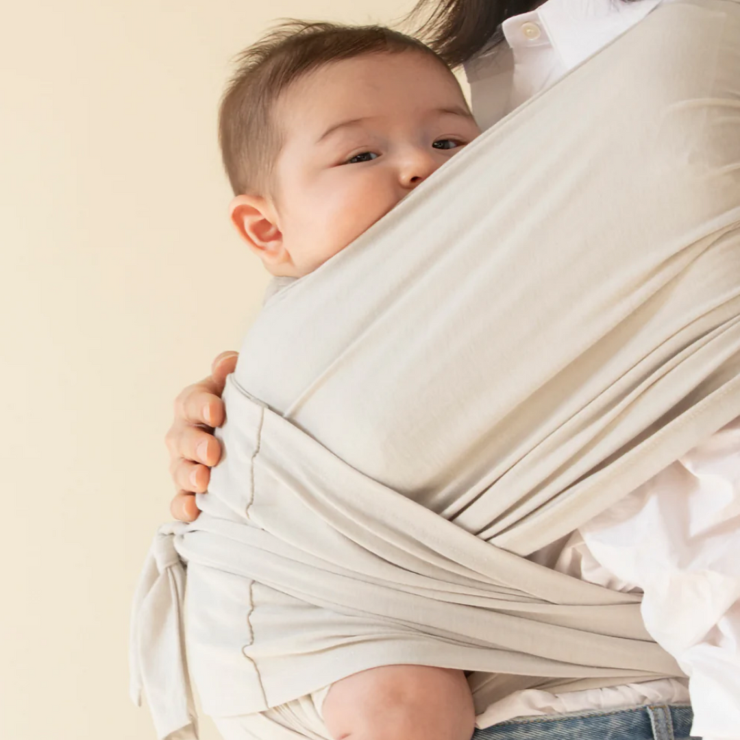 Ouder met baby in ergonomische draagdoek, heeft handen vrij voor activiteiten terwijl baby comfortabel is.